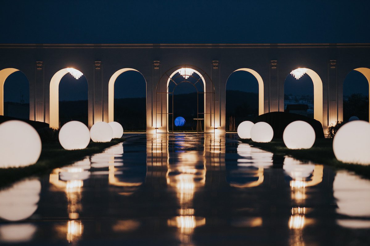 Colonnada și sferele luminoase reflectate în lac noaptea